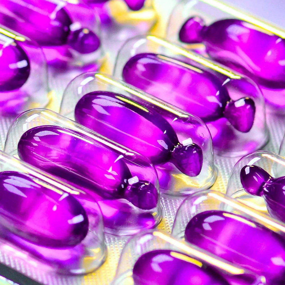 Close-up of purple vegan hair oil capsules in clear blister packaging for hair nourishment and volume enhancement